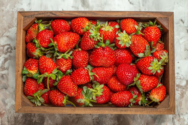 Gros plan sur des fraises fraîches dans une petite boîte en bois marron