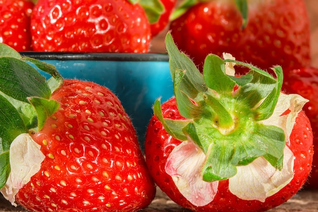Photo gratuite gros plan sur des fraises mûres dans des gouttelettes d'eau posées sur une table en bois idée de récolte de baies saisonnières pour fond de fraise ou préparation de dessert