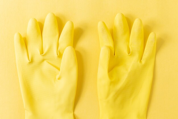 Gros plan de gants en plastique jaune sur une surface jaune