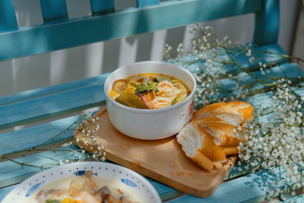 Photo gratuite gros plan en grand angle sur une soupe aux fruits de mer et légumes avec des tranches de baguette sur un banc bleu