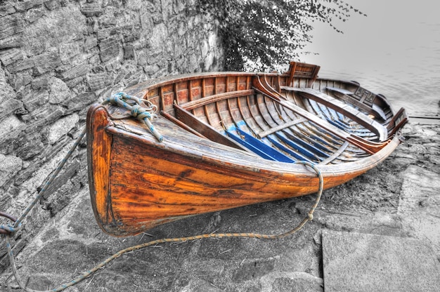 Gros plan grand angle tiré d'un bateau de pêche couché sur les pierres sur le corps du lac