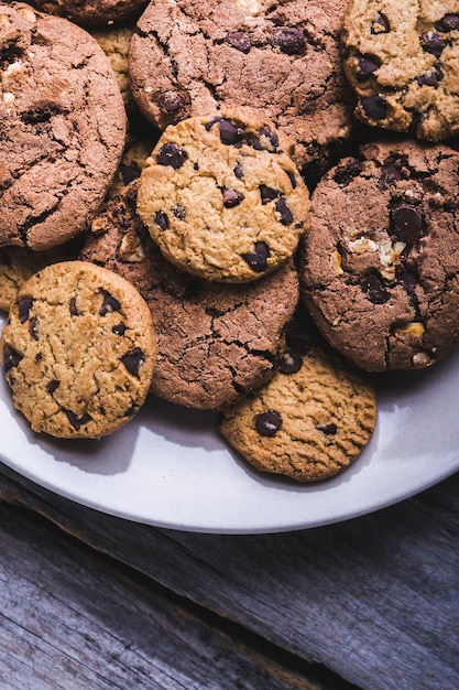 Gros plan d'un grand nombre de cookies aux pépites de chocolat dans une assiette blanche