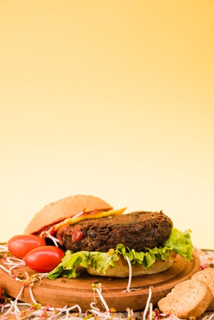 Gros plan, hamburger, à, jolies tomates; pain et laitue sur fond jaune