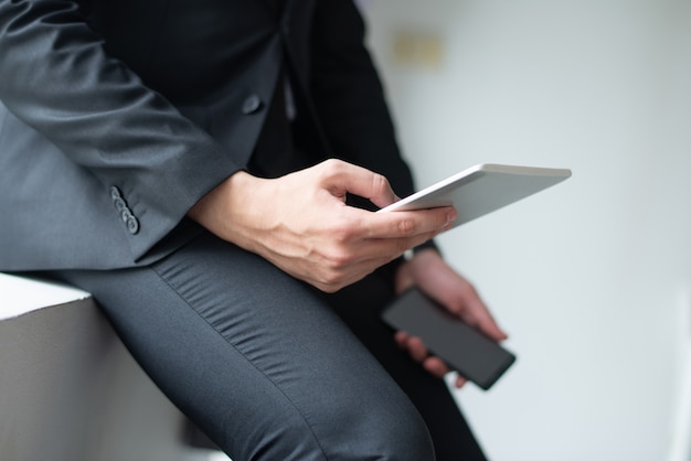 Gros plan d&#39;un homme d&#39;affaires à l&#39;aide de gadgets et s&#39;appuyant sur le rebord