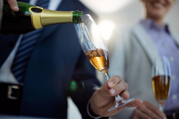 Gros plan sur un homme d'affaires versant du champagne lors d'une fête de bureau