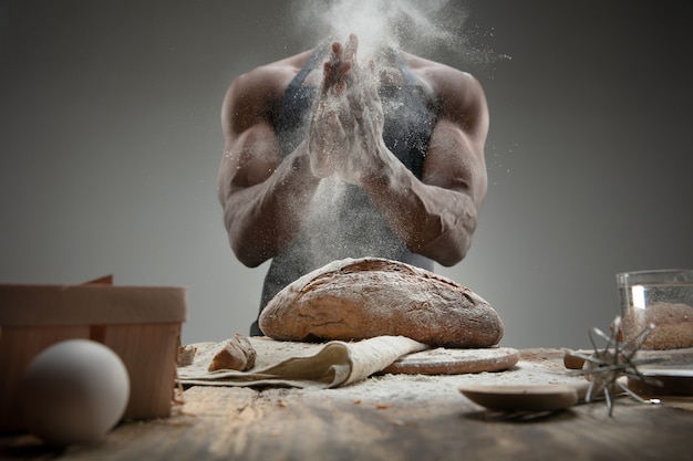 Gros plan d'un homme afro-américain cuit des céréales fraîches, du pain, du son sur une table en bois. Manger savoureux, nutrition, produit artisanal. Nourriture sans gluten, mode de vie sain, fabrication biologique et sûre. Fait main.