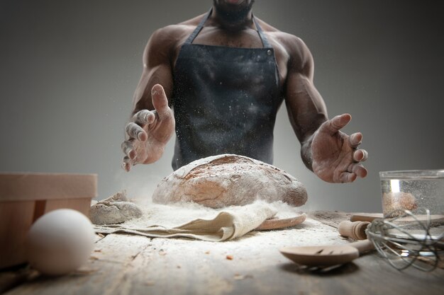 Gros plan d'un homme afro-américain cuit des céréales fraîches, du pain, du son sur une table en bois. Manger savoureux, nutrition, produit artisanal