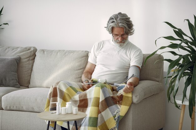 Gros plan d'un homme âgé de 70 à 75 ans mesurant la pression. Homme pour mesurer sa tension artérielle. Santé et soins.