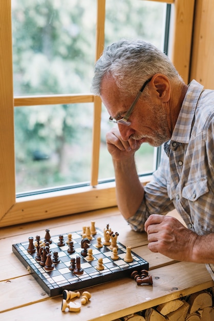 Gros plan, homme aîné, jouer échecs, sur, rebord fenêtre