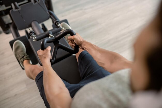 Gros plan d'un homme athlétique faisant de l'exercice sur une machine dans une salle de sport