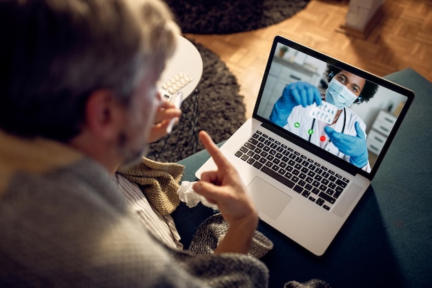 Gros plan d'un homme ayant un appel vidéo avec son médecin le soir à la maison