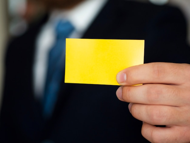 Gros plan homme en costume avec carte de visite jaune