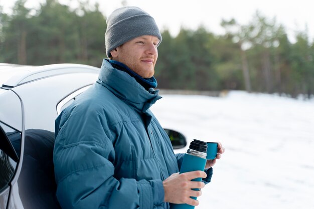 Gros plan sur un homme dégustant une boisson chaude lors d'un voyage d'hiver