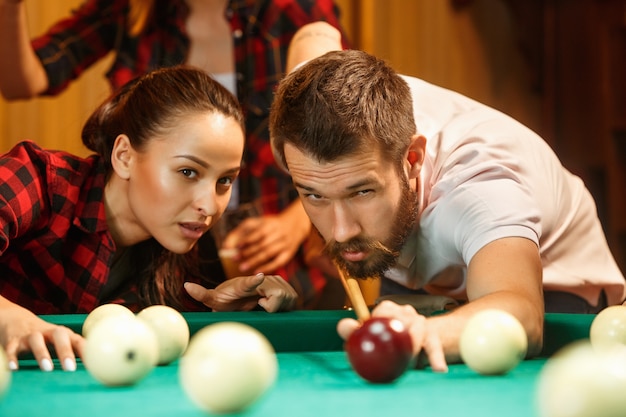 Gros plan d'un homme jouant au billard. modèle caucasien visant soigneusement et vigoureusement par queue en boule. Concept de jeu