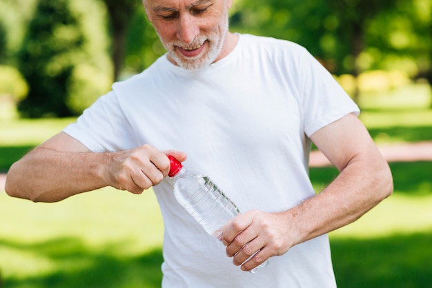 Gros plan homme ouvrant une bouteille d'eau