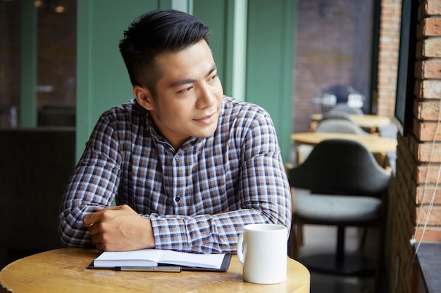 Gros plan d'un homme pensif, regardant la fenêtre du café