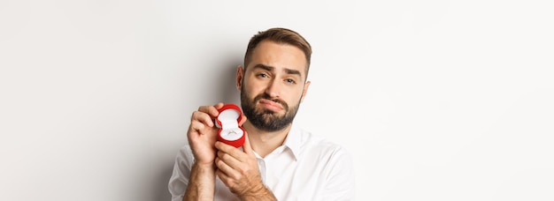 Photo gratuite gros plan d'un homme plein d'espoir qui supplie de l'épouser à la triste et montrant l'anneau de mariage faisant une proposition w