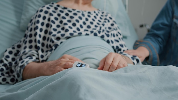 Gros plan d'un homme à la retraite recevant la visite de sa nièce et de sa fille à l'hôpital. Petite fille apportant des fleurs et visitant un patient malade à la clinique médicale, apportant soutien et réconfort pour le rétablissement.