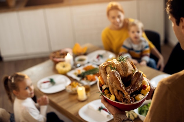 Gros plan sur un homme servant de la dinde de Thanksgiving pendant le déjeuner en famille dans la salle à manger