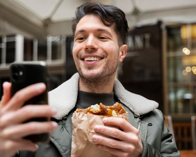 Gros plan sur un homme souriant avec de la nourriture et un téléphone