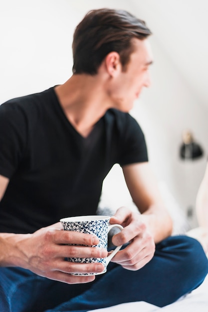 Gros plan d&#39;un homme tenant une tasse en céramique dans ses mains