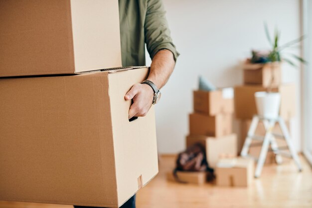 Gros plan d'un homme transportant des boîtes en carton lors d'un déménagement dans un nouvel appartement