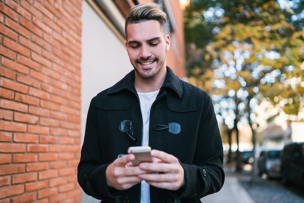 Gros plan d'un homme utilisant son téléphone portable en marchant à l'extérieur dans la rue