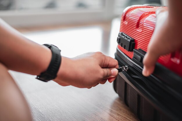 Gros plan d'un homme voyageur a fini de faire ses bagages et les verrouille L'homme prépare des vêtements dans des valises Voyage vacances et concept de vacances