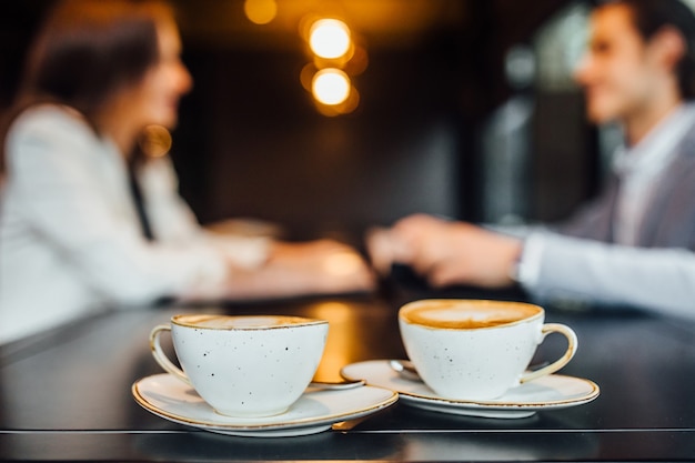 Photo gratuite gros plan image de deux tasses à café avec café au lait sur table en bois au café.