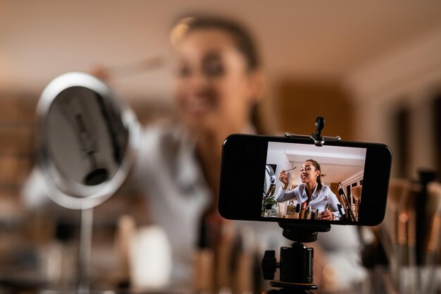 Gros plan d'une influenceuse appliquant des produits de beauté pendant le tournage d'un vlog de maquillage