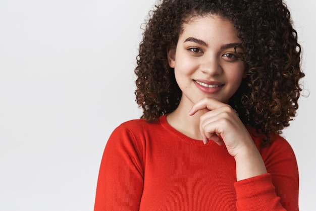 Gros plan intelligent curieux beau femme intelligente sombre coiffure bouclée toucher le menton souriant satisfait audition idée intéressante réfléchir décision regarder pensif ravi fond blanc