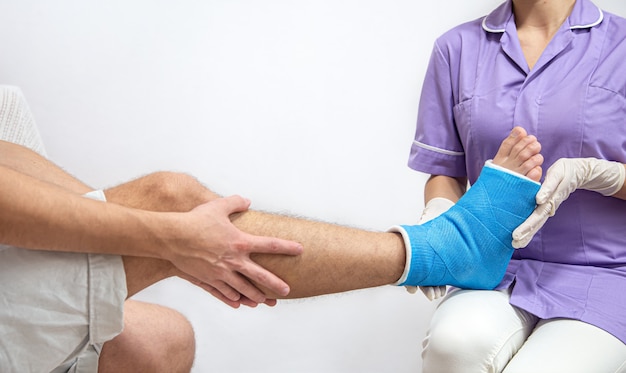 Gros plan de la jambe d'un homme dans un plâtre et une attelle bleue après un bandage dans un hôpital.