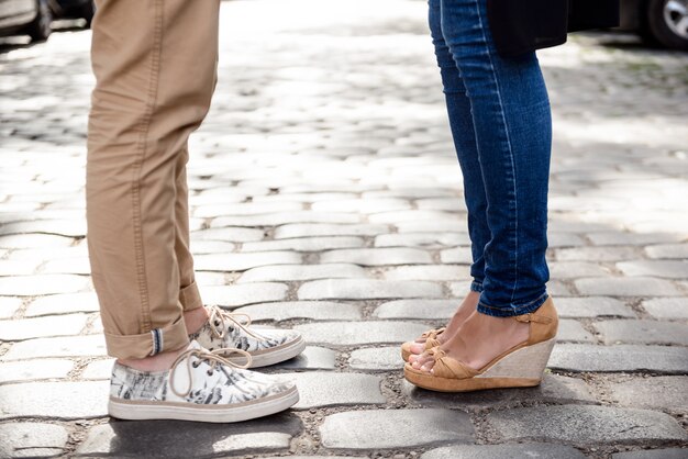 Gros plan des jambes du couple en keds debout dans la rue.