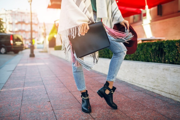Gros plan des jambes de femme portant des bottes en cuir noir, des jeans, des tendances de printemps de chaussures, sac de tenue