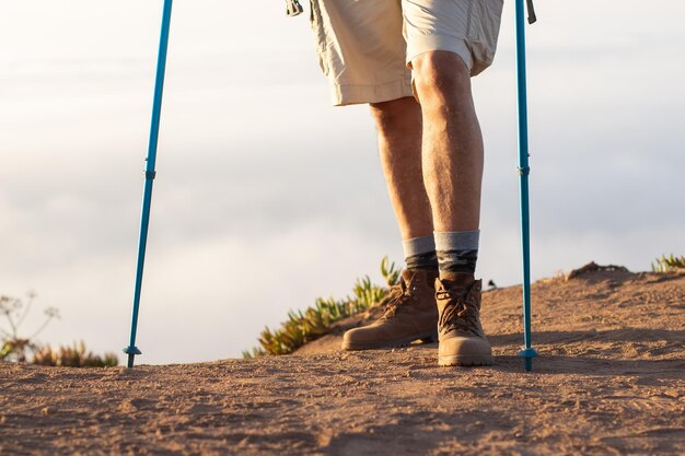 Gros plan sur les jambes d'un randonneur masculin. Voyageur debout au bord de la falaise. Sport, aventure, concept de voyage