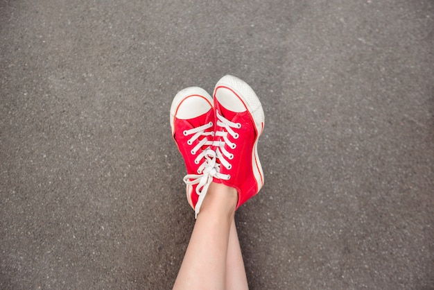 Gros plan des jambes en rouge keds couché sur l'asphalte.