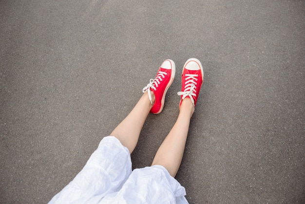 Gros plan des jambes en rouge keds couché sur l'asphalte.