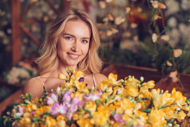 Gros plan, jaune, fleurs, bouquet, devant, jeune femme blonde, regarder, appareil-photo