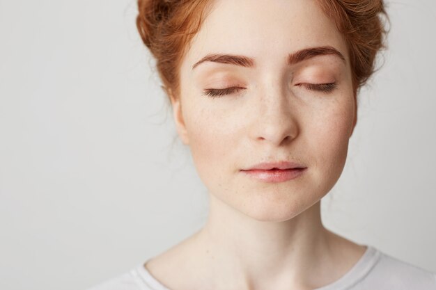 Gros plan d'une jeune belle rousse aux yeux fermés. Copiez l'espace.