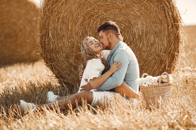 Gros plan d'un jeune couple assis dans le champ de blé. Les gens sont assis sur une botte de foin sur la prairie et les embrassent.
