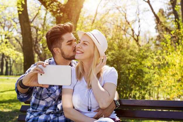 Gros plan d'un jeune couple séduisant prenant un selfie heureux dans un parc