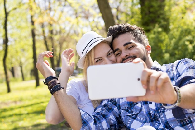Gros plan d'un jeune couple séduisant prenant un selfie heureux dans un parc