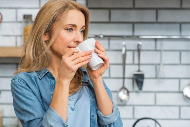 Gros plan d&#39;une jeune femme buvant une tasse de café