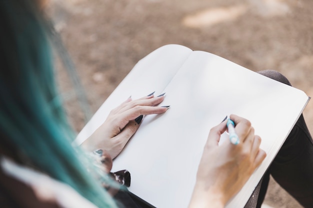 Gros plan, jeune, femme, dessin, plaine, cahier, stylo