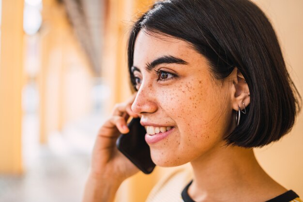 Gros plan d'une jeune femme latine parlant au téléphone à l'extérieur dans la rue. Concept urbain.