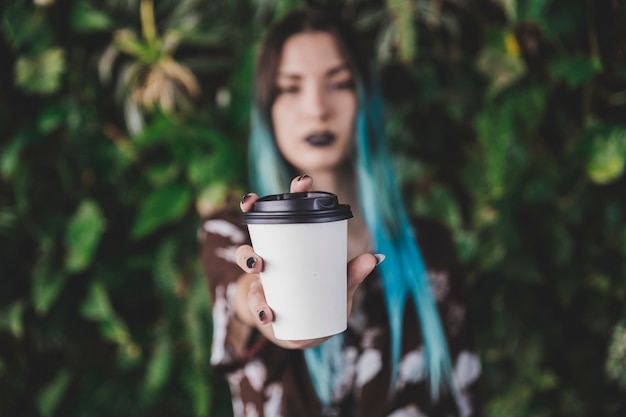 Gros plan d&#39;une jeune femme montrant une tasse de café à emporter