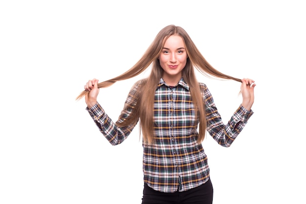 Gros plan d'une jeune femme positive touchant ses cheveux isolé sur mur blanc