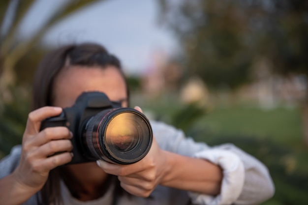 Gros plan jeune femme à prendre des photos à l'extérieur sur un appareil photo reflex professionnel.