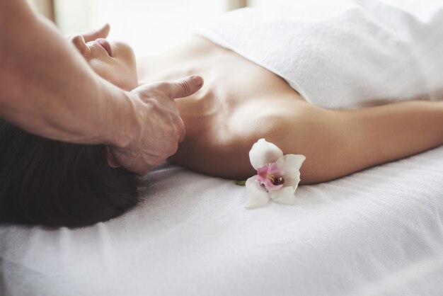 Gros plan d'une jeune femme reçoit un massage au salon de beauté. Procédures pour la peau et le corps.