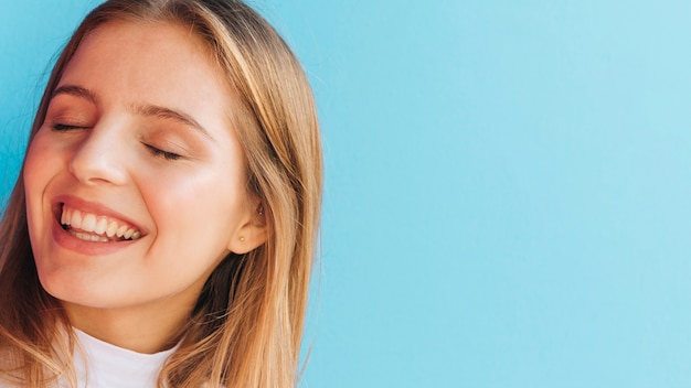 Photo gratuite gros plan d'une jeune femme souriante sur fond bleu